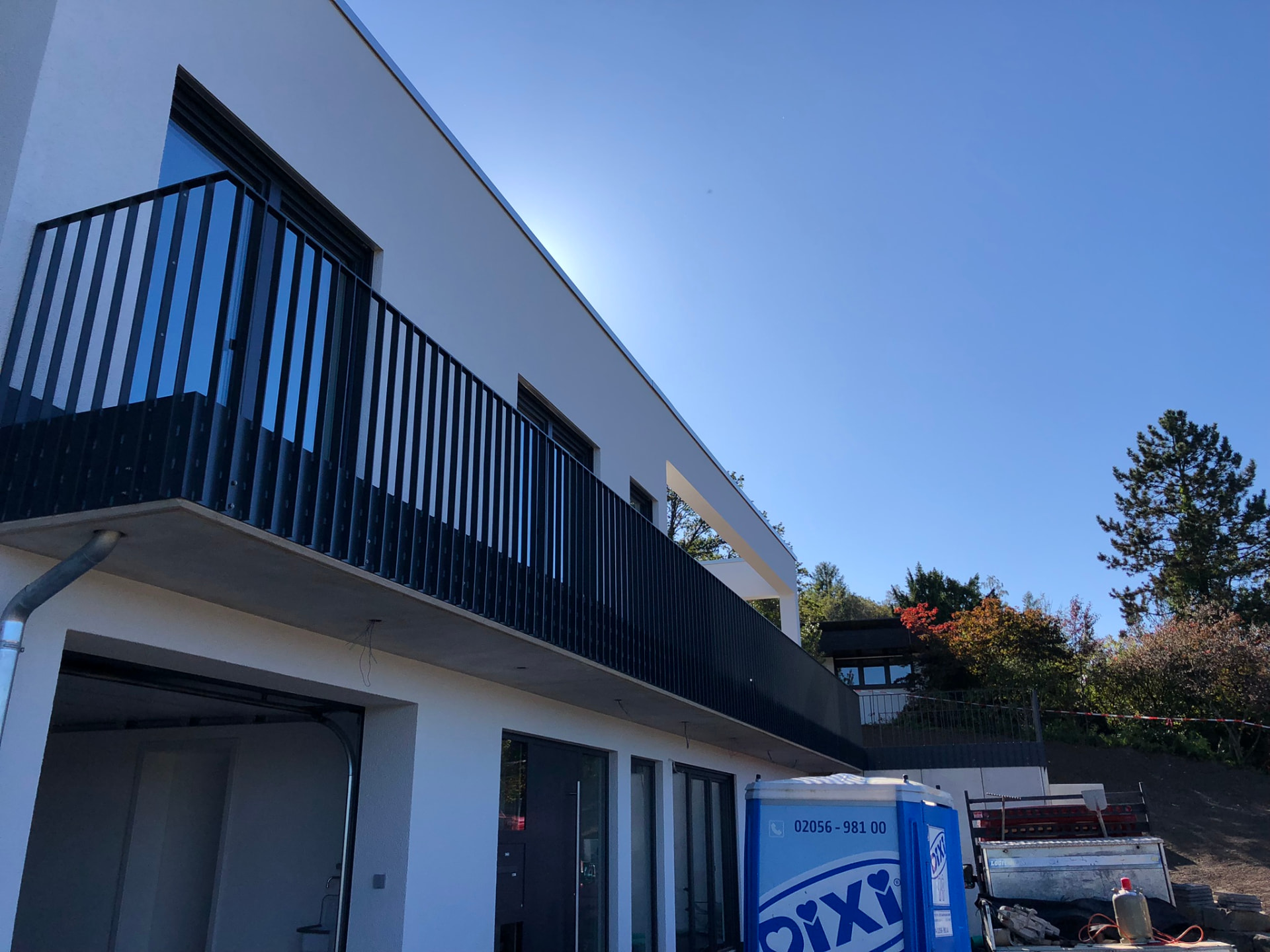 Anthrazitfarbenes Stabgeländer auf einem langen Balkon eines Neubaus