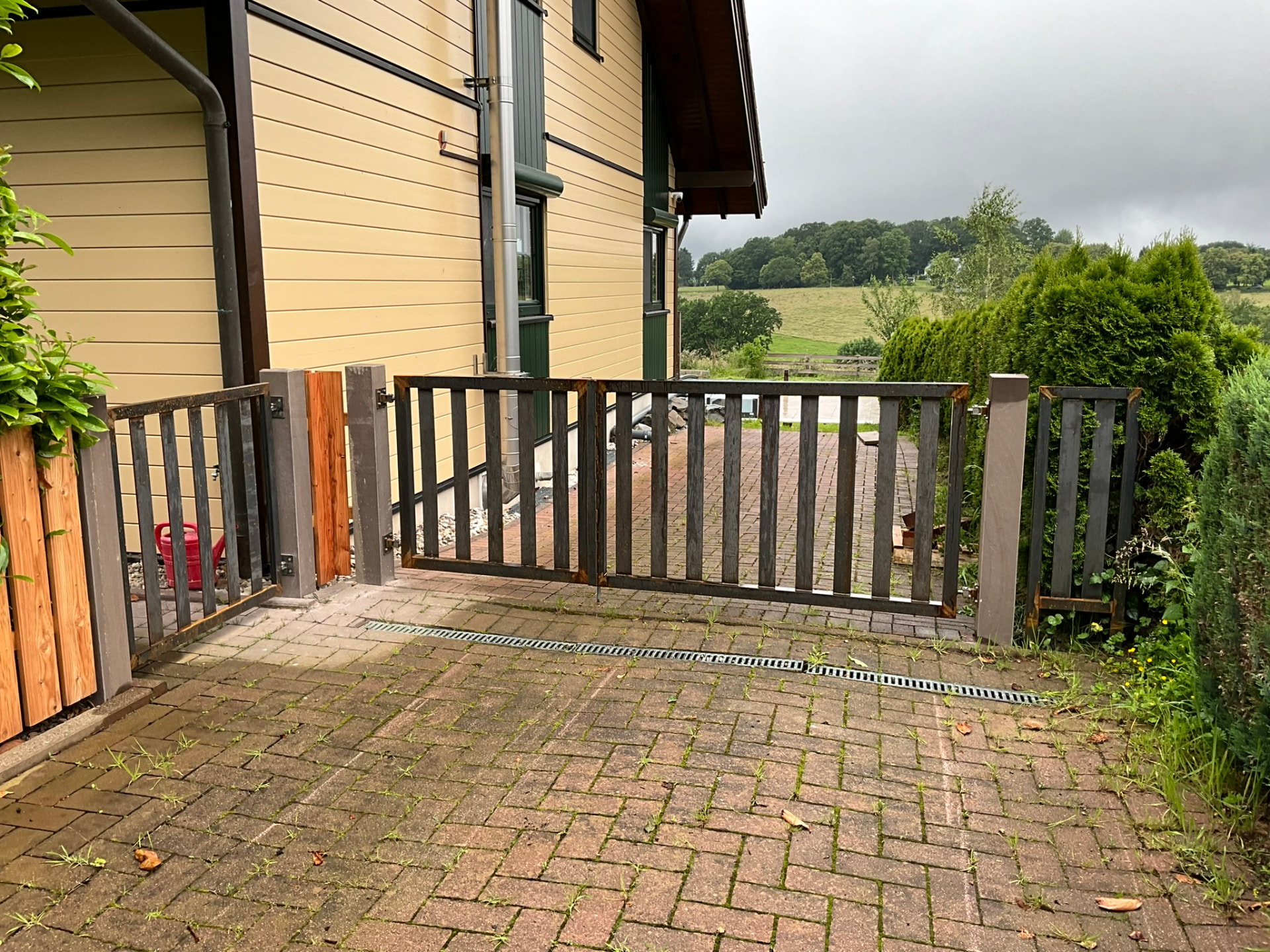 Zaunanlage mit Gehtür in Stahl und Holz an einer Hofeinfahrt